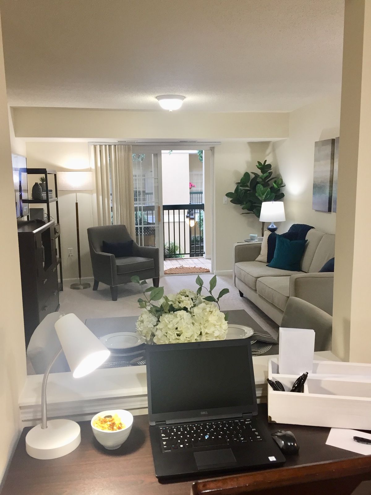A modern living room with stylish furniture, including a sofa, armchair, lamps, and decorative plants.