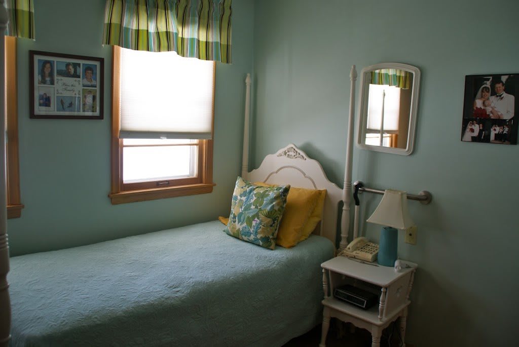 A cozy bedroom with a single bed next to a nightstand and mirror.