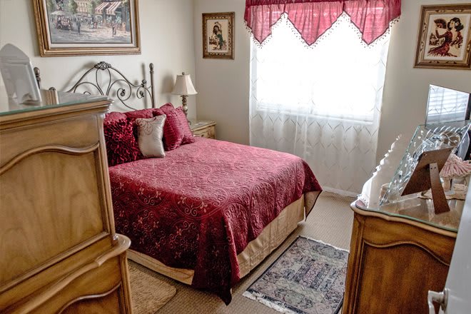 A cozy bedroom with classic wooden furniture and a richly colored bedspread.