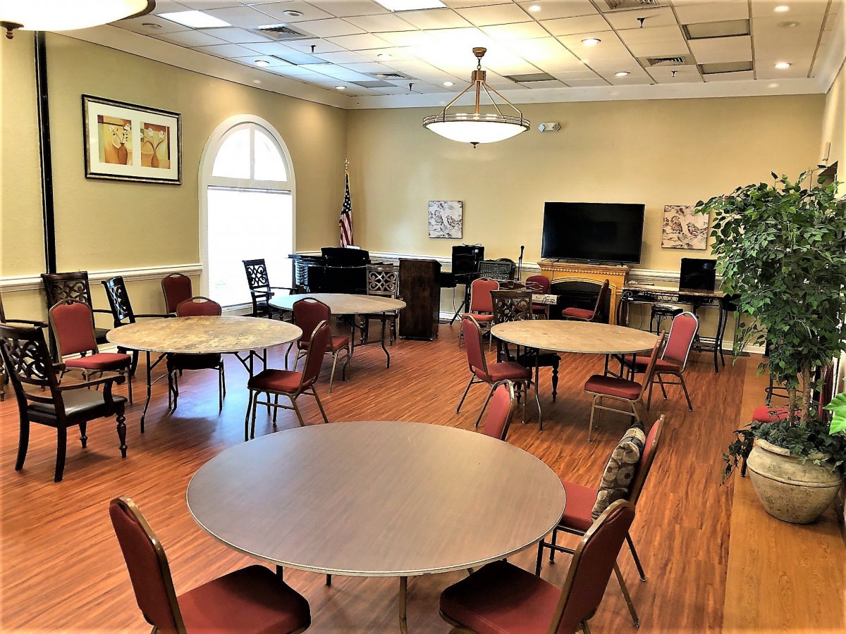 A well-lit meeting room with round tables and chairs, equipped with a screen for presentations.