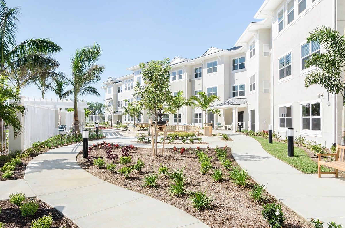 A modern apartment complex with landscaped walkways and palm trees.