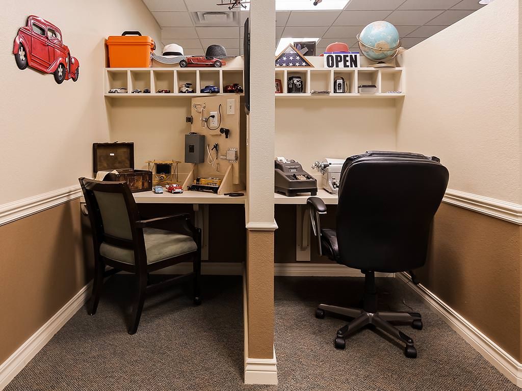 A neatly organized office workspace with two desks and chairs, decorated with shelves and various items.