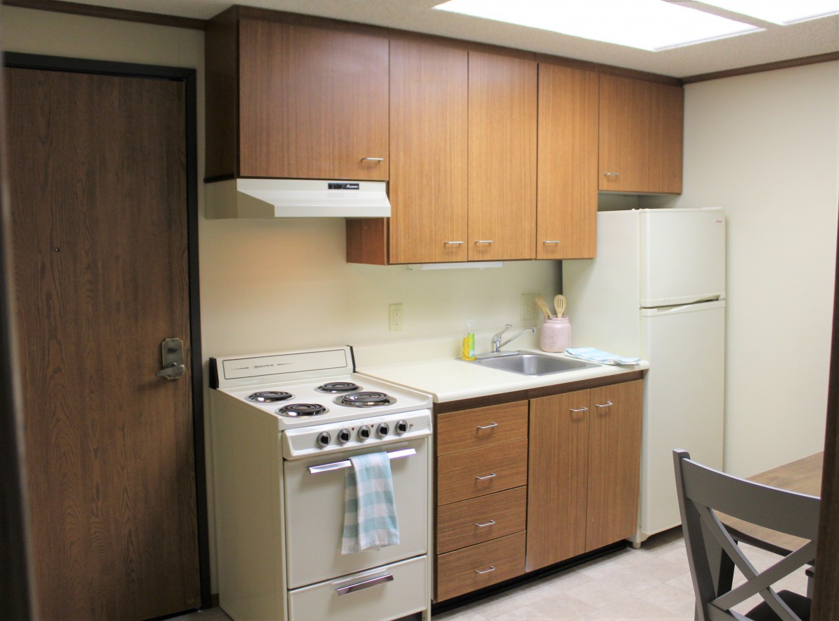 A compact kitchen with wooden cabinets, a stove, and a refrigerator.