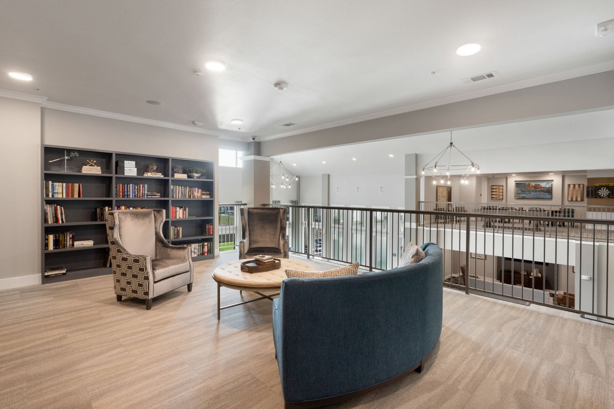 A cozy living room with modern furniture and a bookshelf, providing a comfortable seating area.