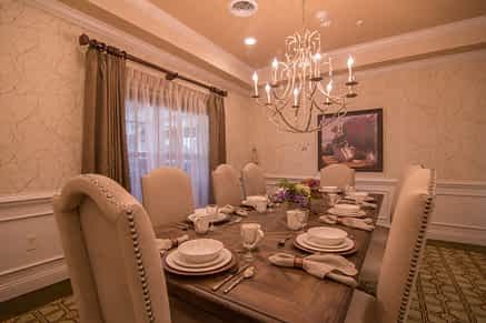 An elegantly set dining room table with a chandelier overhead.