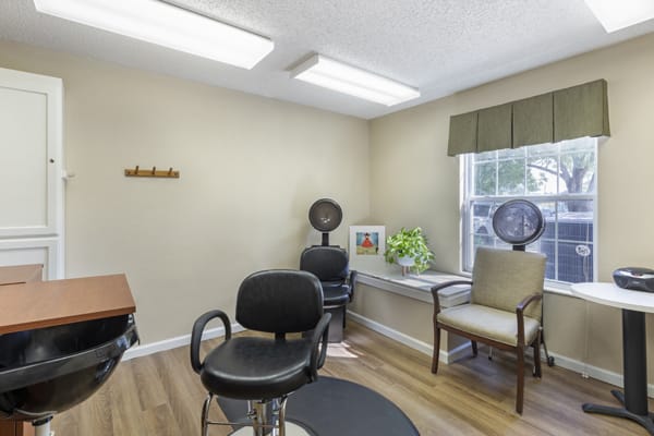 A small, cozy hair salon with chairs and a hair dryer in a well-lit room.