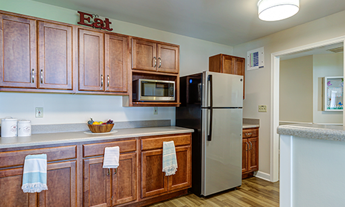 A modern kitchen featuring wooden cabinets, a stainless steel refrigerator, and a microwave.