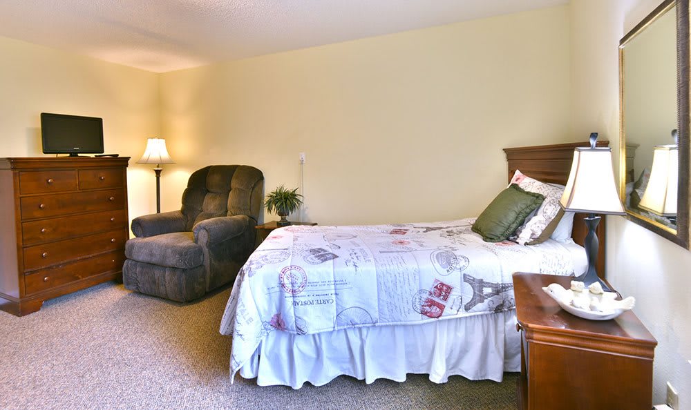 A cozy bedroom featuring a single bed, an armchair, and soft lighting.