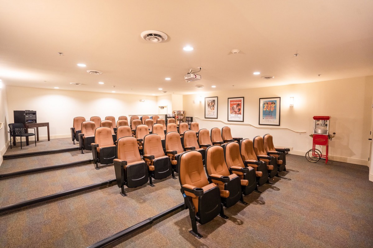 A small theater room with tiered seating and a projector.