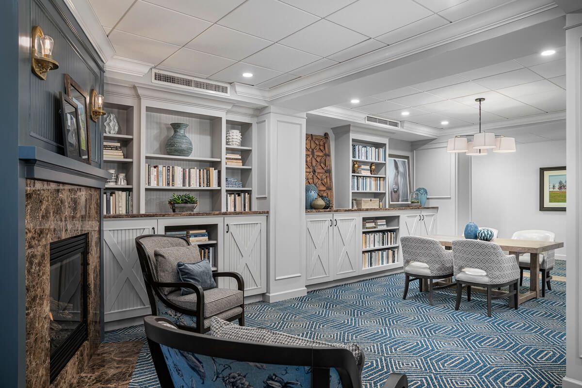 A cozy library room with built-in bookshelves, comfortable seating, and elegant lighting.