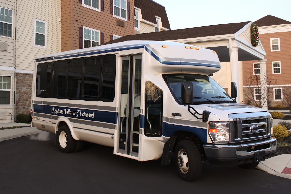 A shuttle bus parked in front of a residential building with its door open.