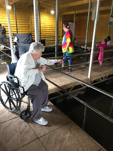 An elderly woman in a wheelchair interacts with children in an indoor setting.