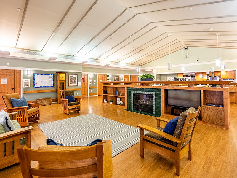 A modern library interior with wooden furniture and bookshelves, featuring a fireplace.