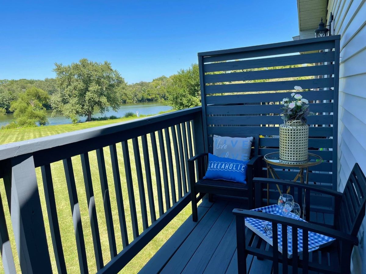A cozy balcony with seating overlooking a picturesque lake and nature scenery.