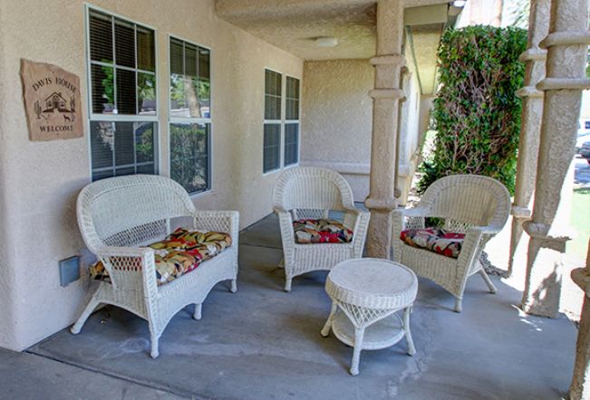 A cozy outdoor patio setup with wicker chairs, a table, and colorful cushions.