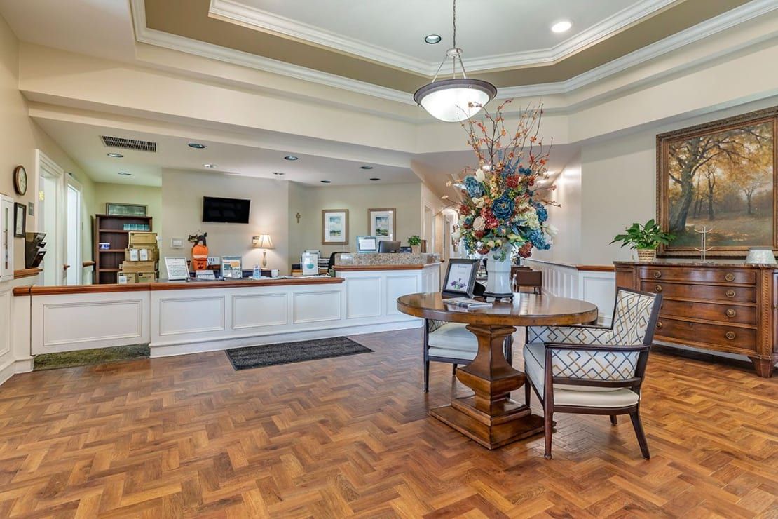 A well-lit reception area featuring a front desk, comfortable seating, and elegant floral arrangements.