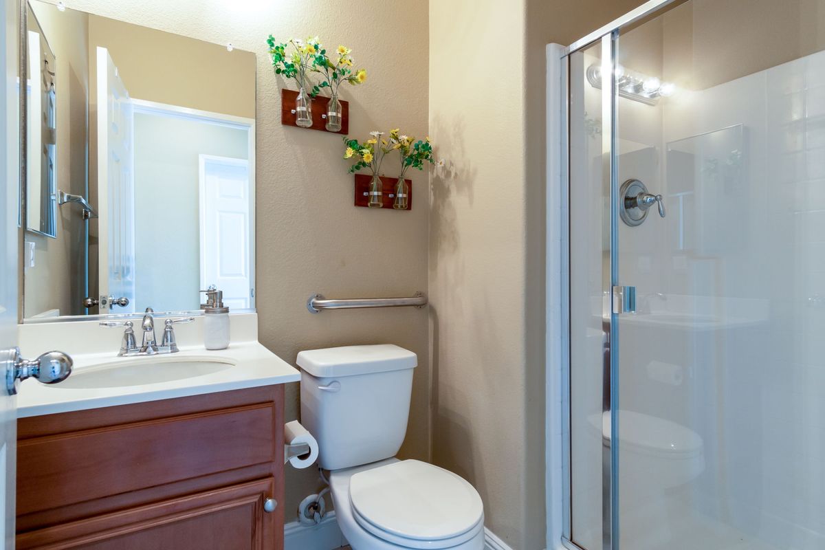 A modern bathroom featuring a toilet, shower, and a vanity with a sink, complemented by decorative wall plants.