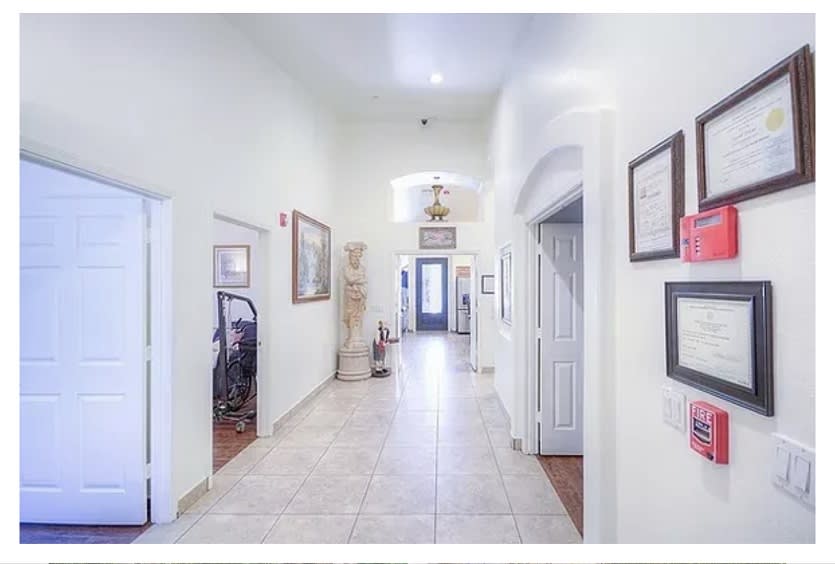 A bright hallway with tiled flooring and decorated walls, leading to multiple rooms.