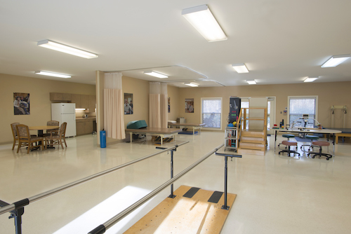 A spacious physical therapy room equipped with exercise bars and rehabilitation tools.