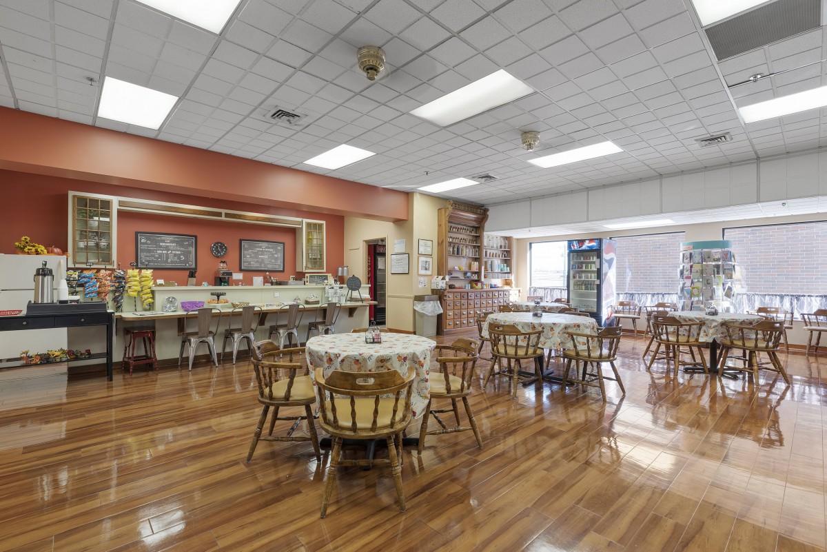 An empty cafeteria with wooden floors, tables, and chairs.