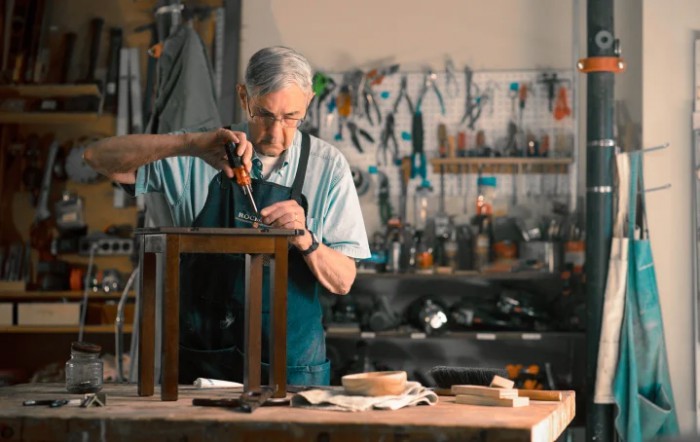 An artisan skillfully working on a wooden piece in a well-equipped workshop.