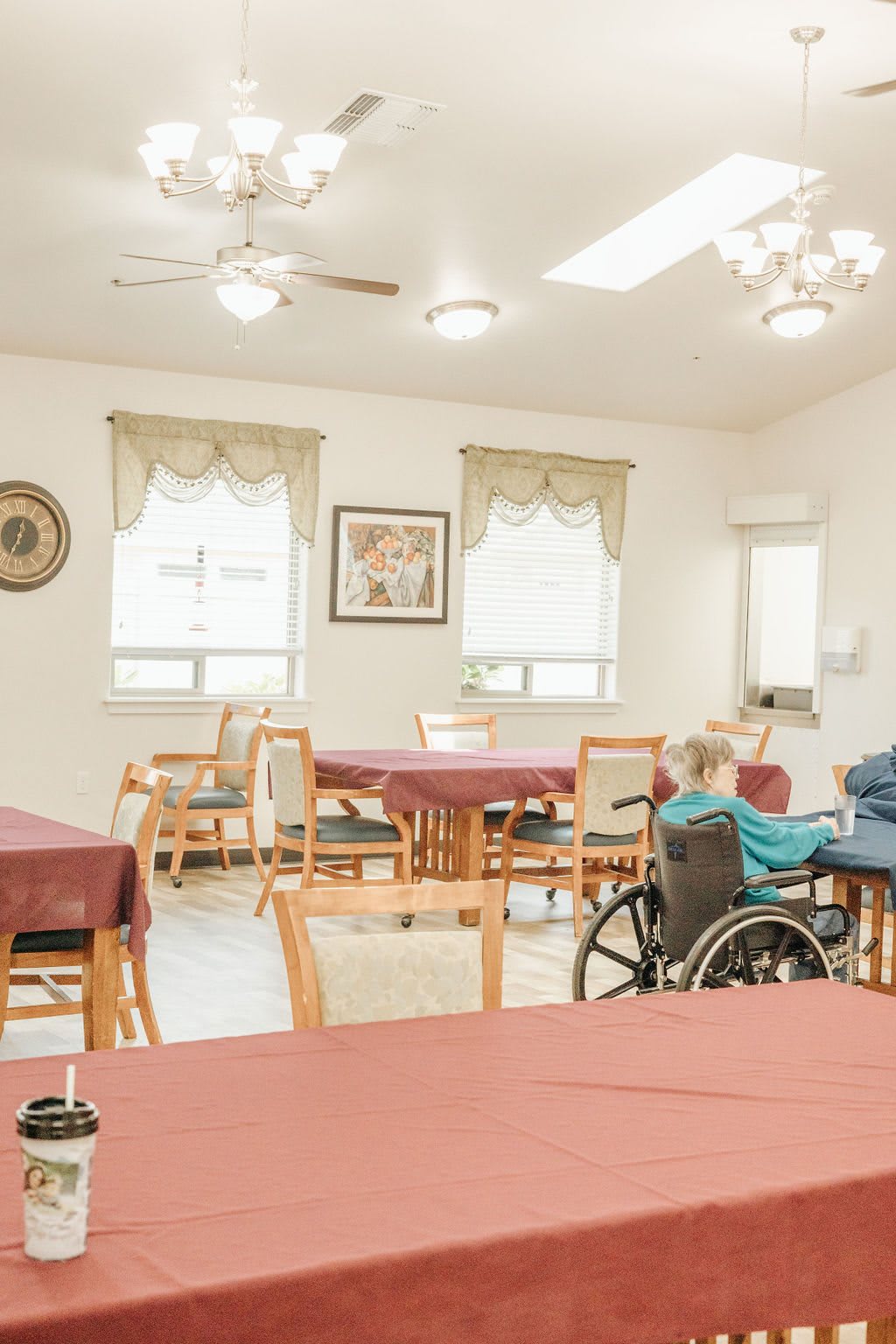 A tranquil dining area with tables, chairs, and an elderly person in a wheelchair.