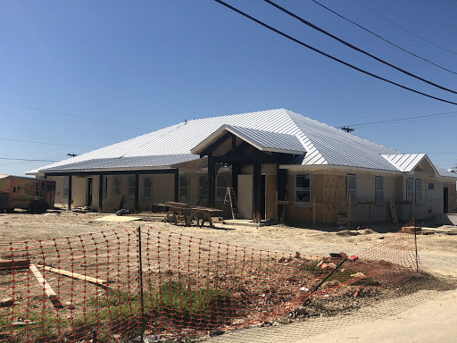 A newly constructed residential building with a metal roof, still in the early stages of completion.