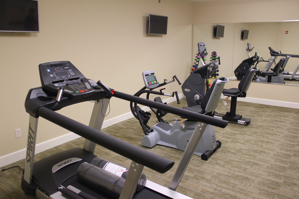 A small indoor gym featuring various exercise equipment, including treadmills and stationary bikes.
