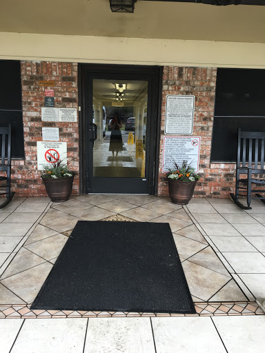 Entrance to a welcoming building with rocking chairs and potted plants.