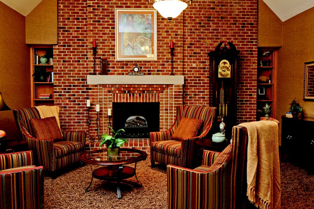 A cozy living room with a brick wall, featuring a fireplace and comfortable armchairs.