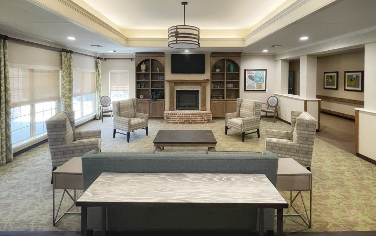 A modern and spacious living room with comfortable seating and a central fireplace.