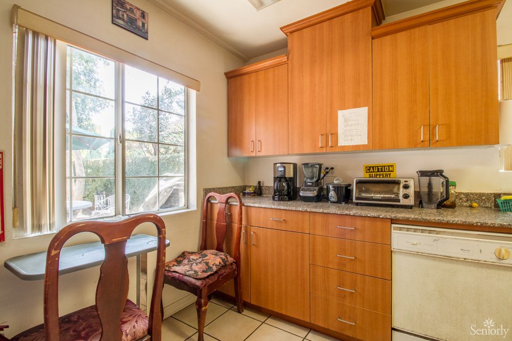 A cozy kitchen with wooden cabinets, a countertop with appliances, and a window providing natural light.