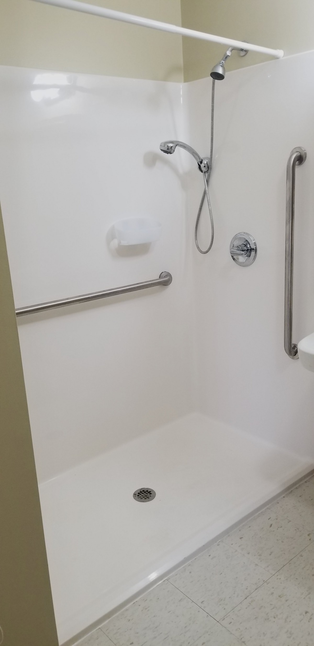 A clean, accessible shower with a handheld shower head and grab bar.