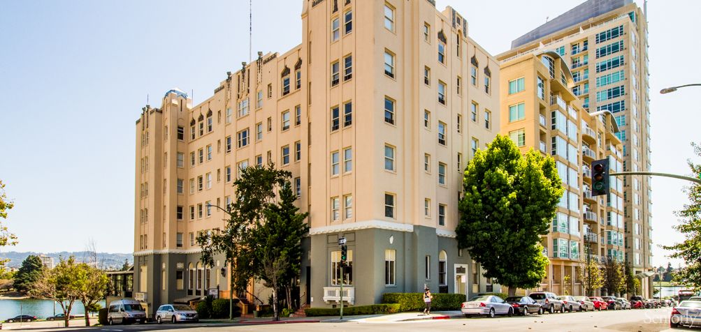 A multi-story apartment building on a street corner surrounded by trees.