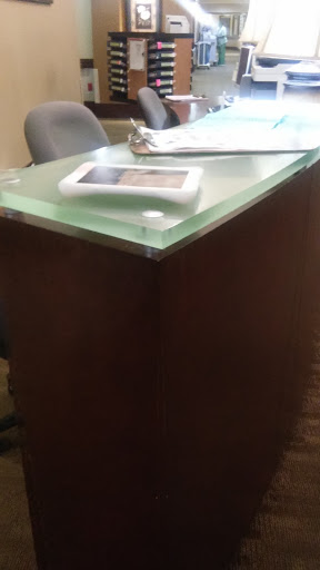 A modern office table featuring a glass top and wooden base.