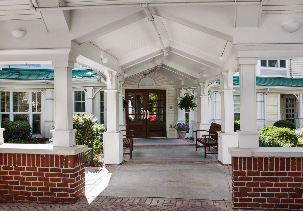 Covered entrance with benches and plants.