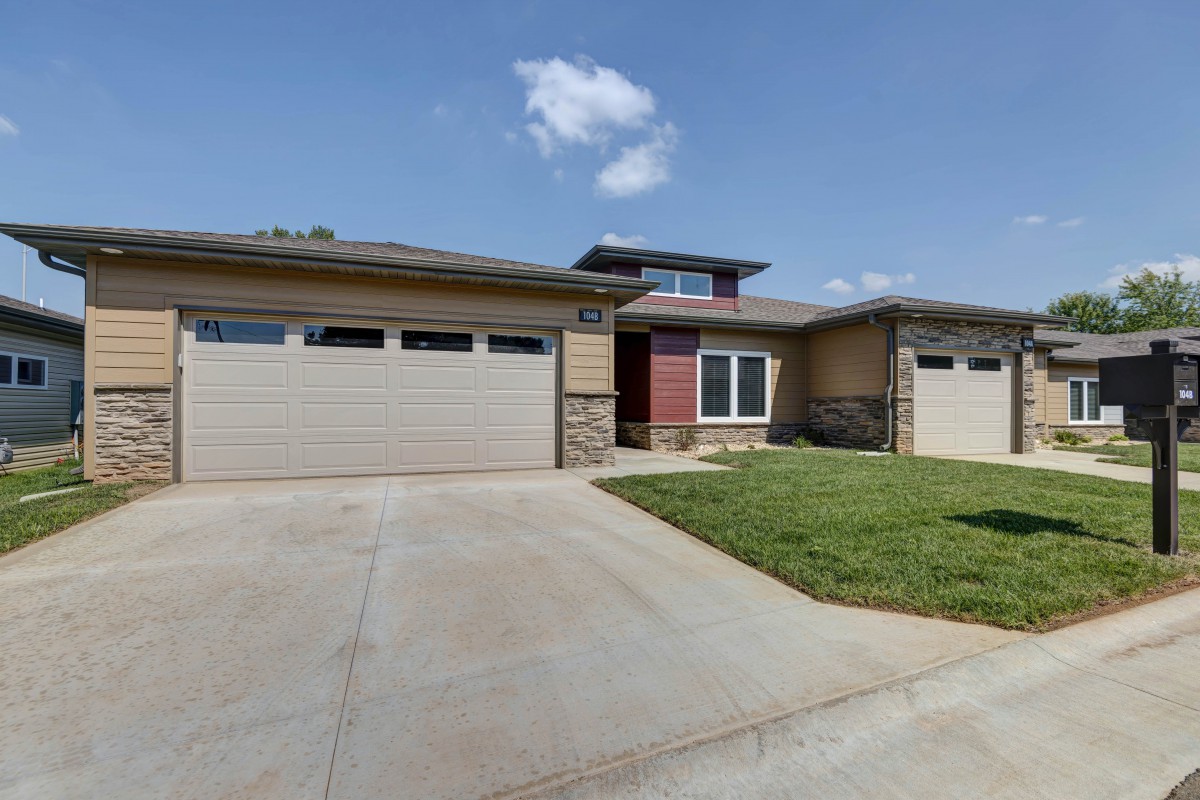 A modern suburban house with a three-car garage and a concrete driveway.