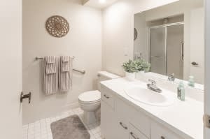 A modern, clean bathroom with a sink, mirror, and shower.