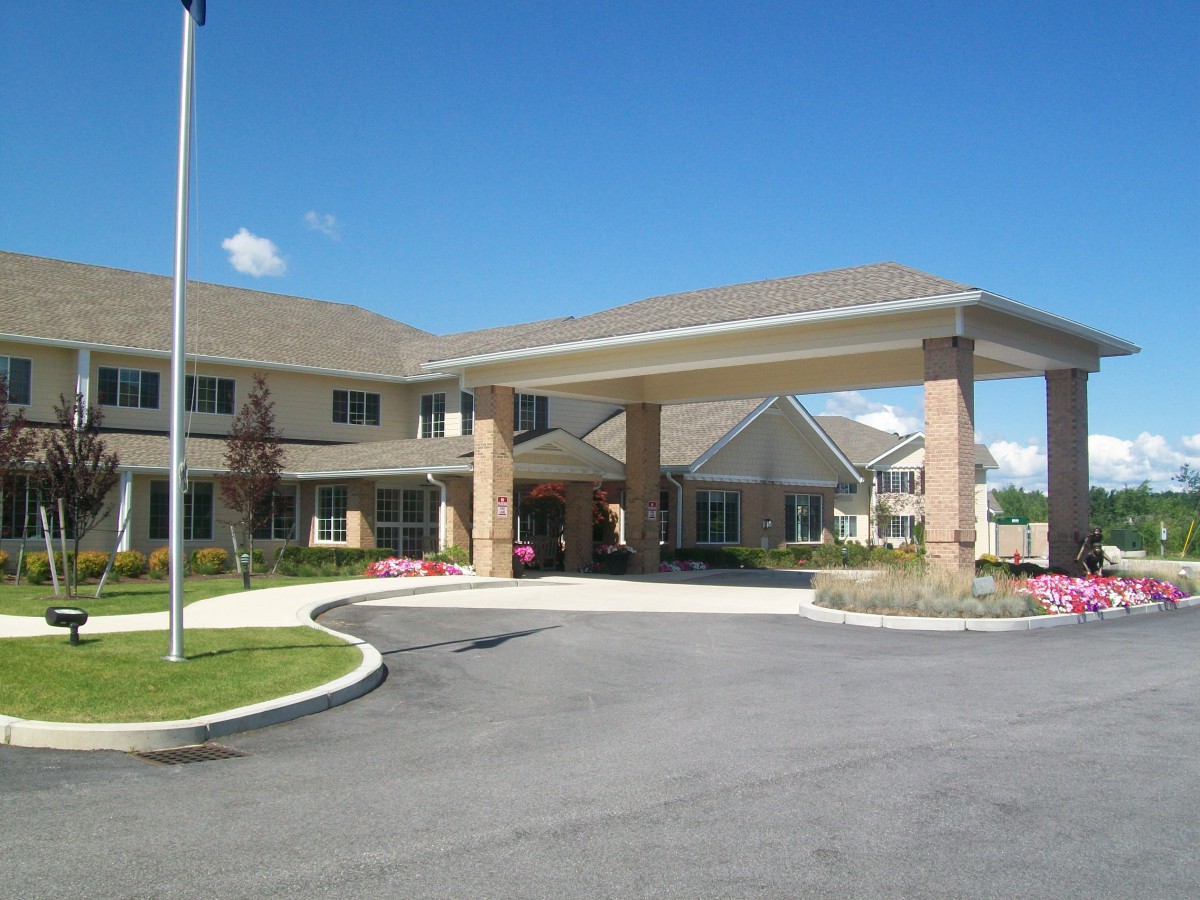 A two-story building with an entrance canopy and driveway under a clear blue sky.