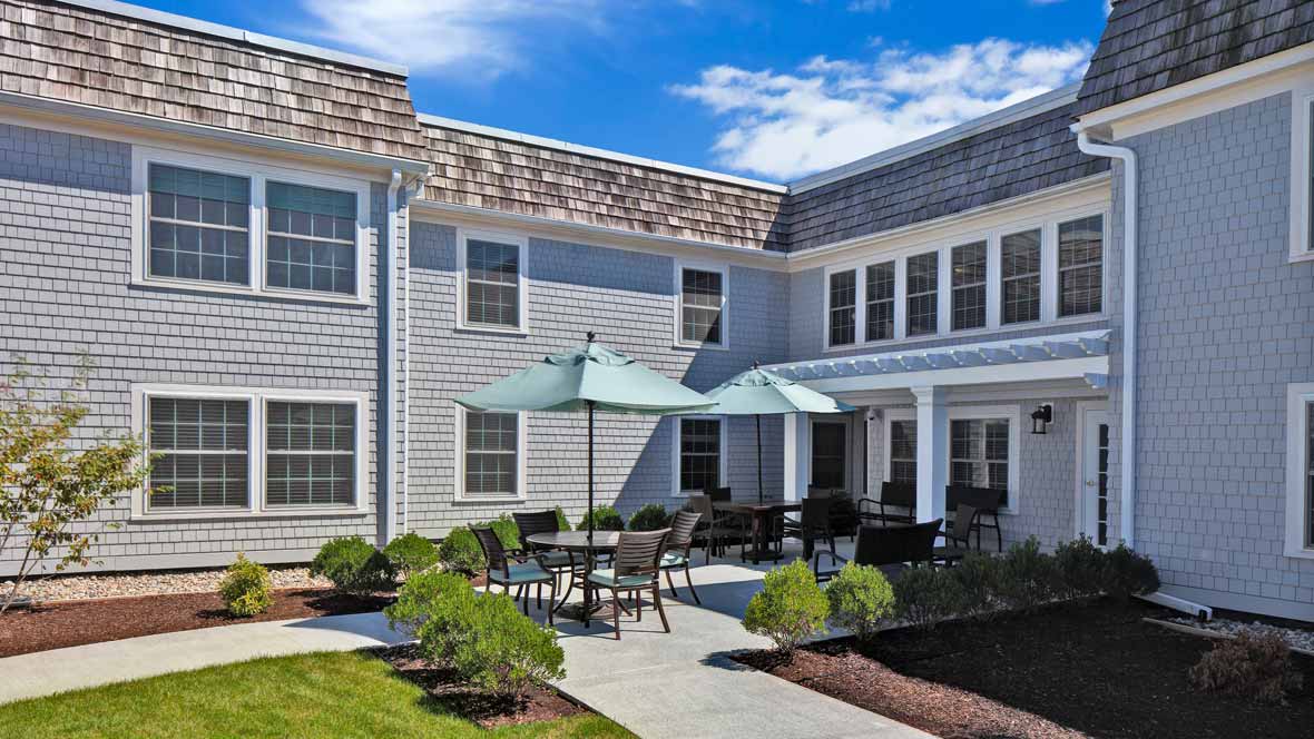 A residential building with outdoor seating and umbrellas on a sunny day.