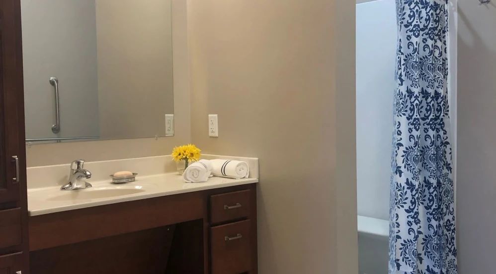 A clean and modern bathroom with a vanity, mirror, and fresh towels.