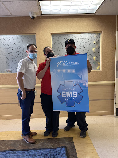 Three individuals in a hospital setting celebrating EMS recognition with a banner.
