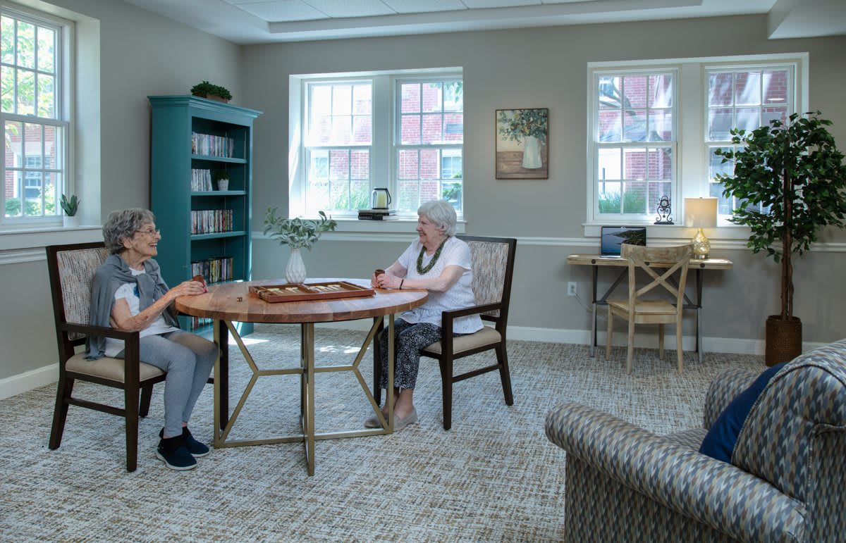 Two elderly individuals sitting at a table in a cozy room.