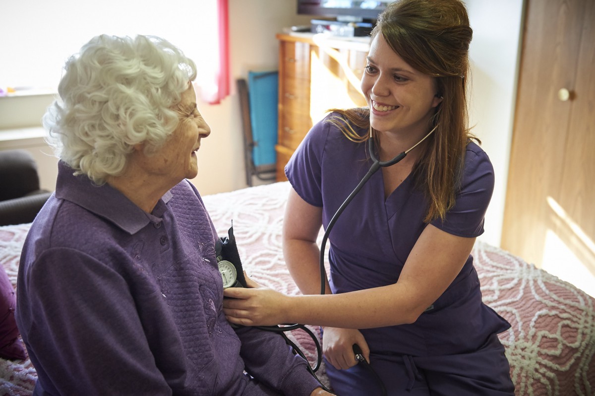 A nurse conducting a medical checkup on an elderly patient at home.