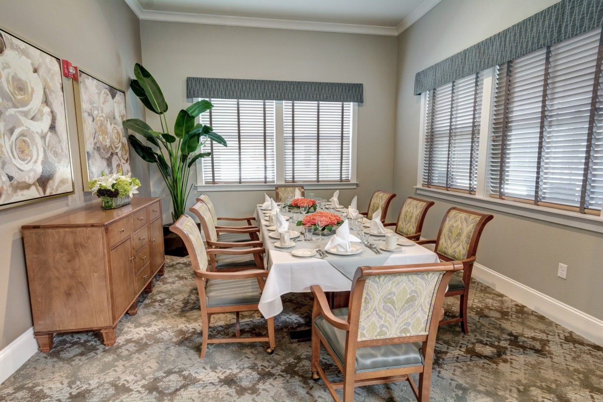 A formal dining room with a table set for a meal, featuring elegant chairs and decorative elements.
