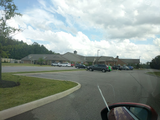 A view of a parking lot with several vehicles and a building under a cloudy sky.