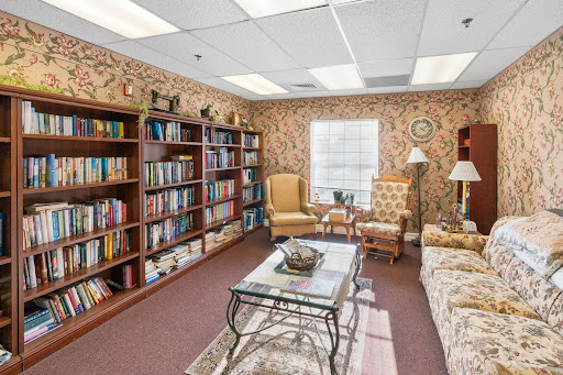 A cozy office space featuring a small library area with bookshelves, comfortable seating, and warm lighting.