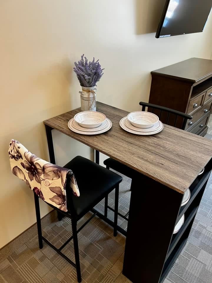 A cozy dining setup featuring a wooden table with two plates and a vase of lavender.