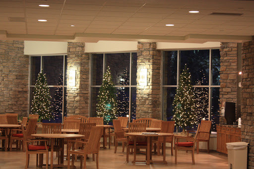 A cozy dining area decorated for the holiday season, featuring beautifully lit Christmas trees by the window.