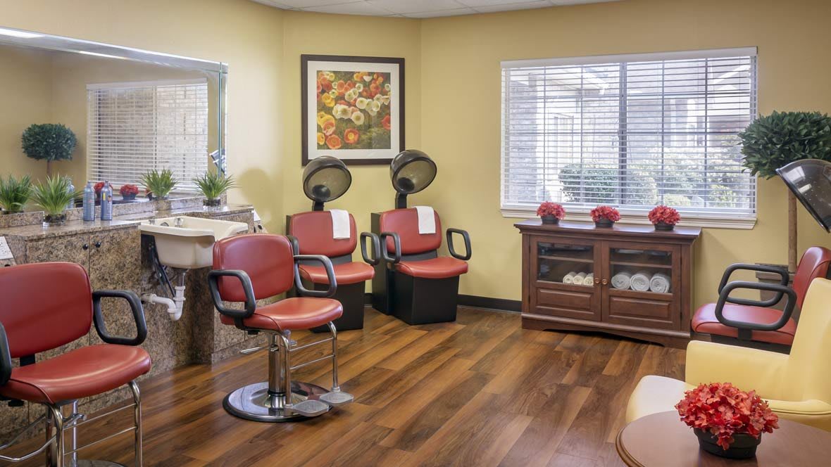 A cozy hair salon with red chairs, hair dryers, and wooden flooring.